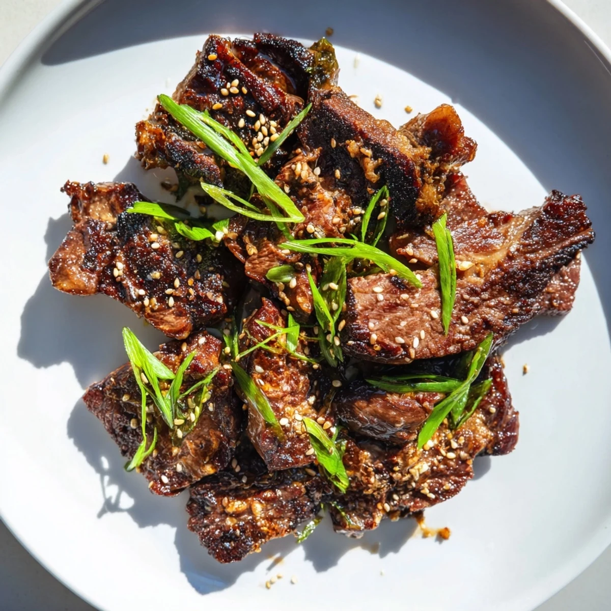 Plate of Korean galbi grilled ribs with caramelized char marks and sesame seed garnish