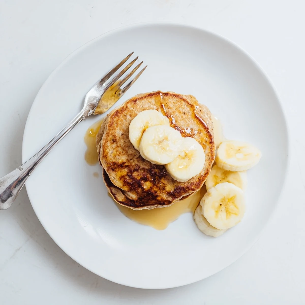 Golden stack of fluffy Greek yogurt banana pancakes drizzled with maple syrup and fresh berries