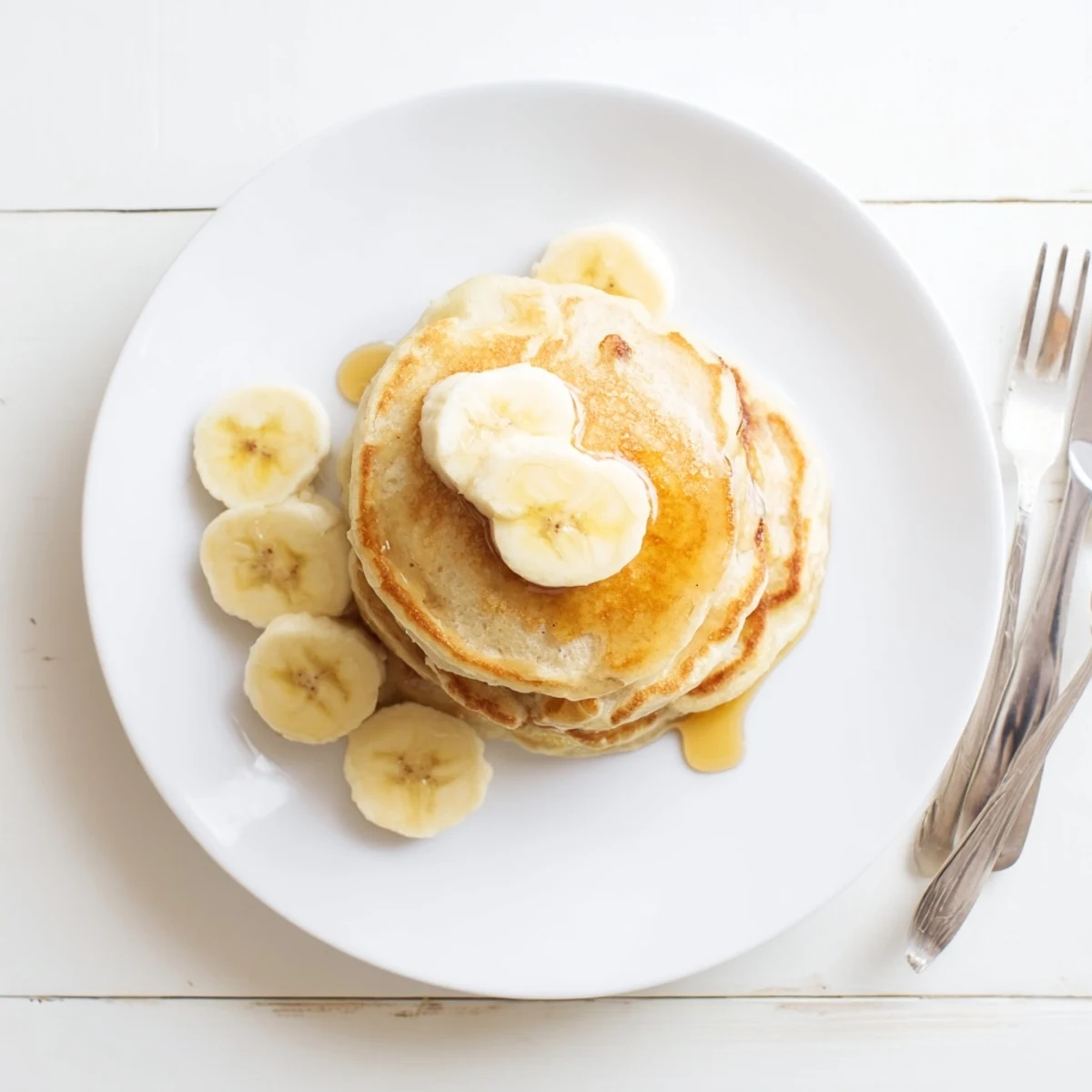 Wholesome breakfast featuring golden Greek yogurt banana pancakes topped with butter and colorful fresh fruit