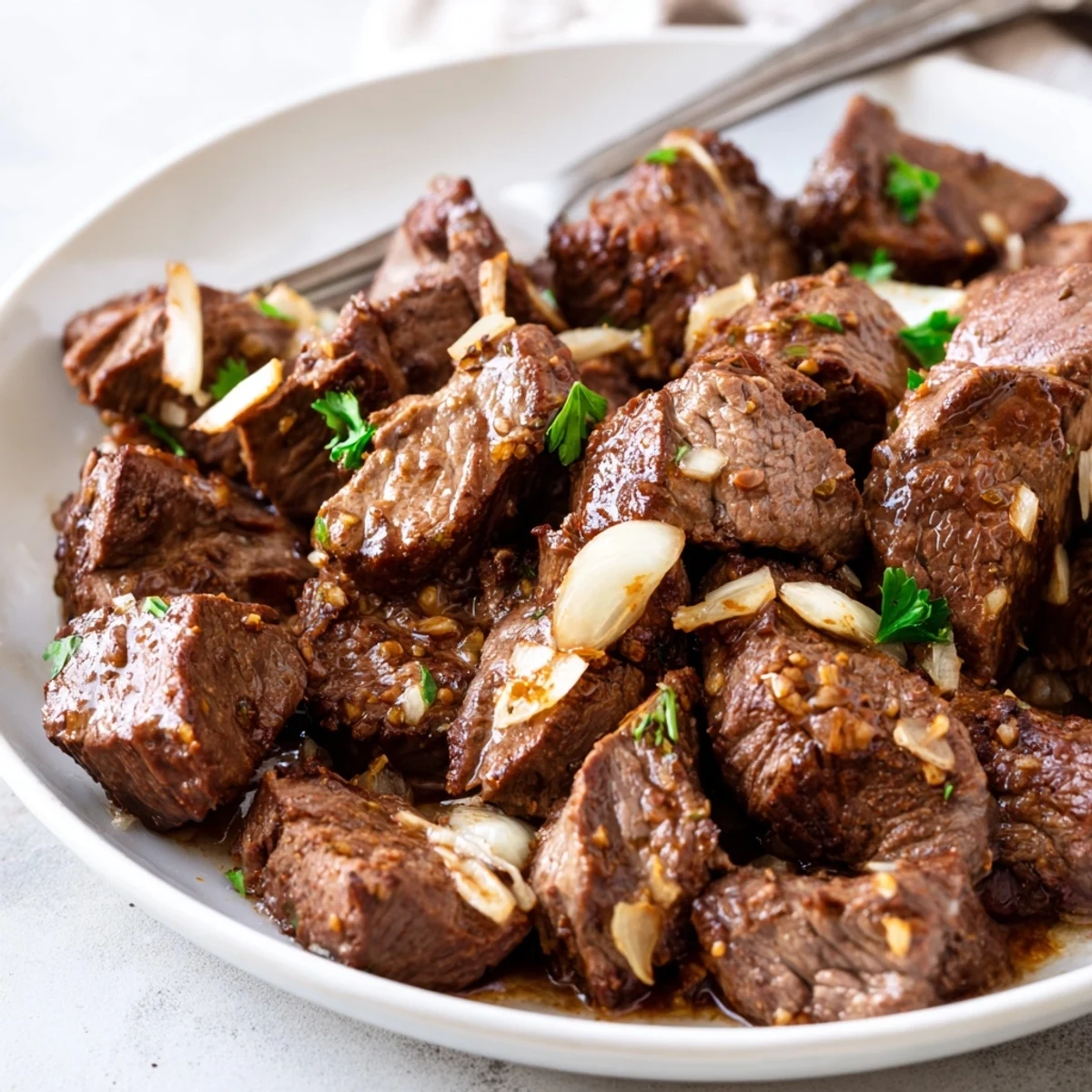 Golden brown crockpot steak bites simmered in garlic butter broth with fresh parsley garnish