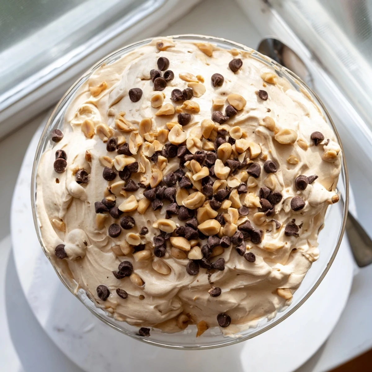 Creamy peanut butter and Cool Whip mousse topped with chopped roasted peanuts and mini chocolate chips in clear glass serving dishes