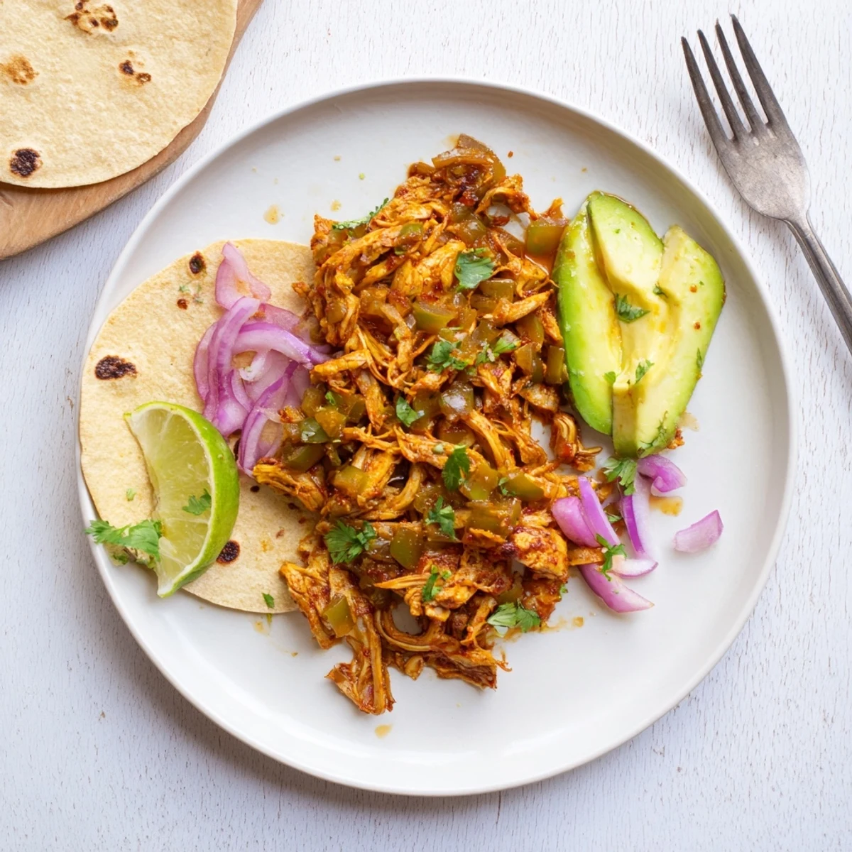 Heaping pile of savory vegan carnitas featuring tender seasoned mushrooms alongside avocado slices and warm tortillas
