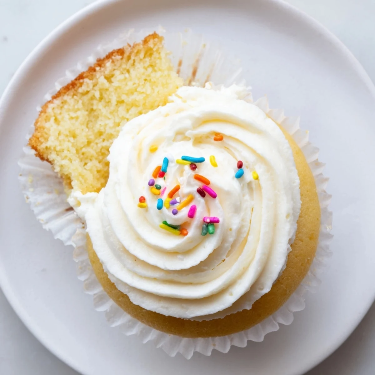 Light and fluffy vanilla cupcakes topped with creamy white buttercream frosting on a decorative plate
