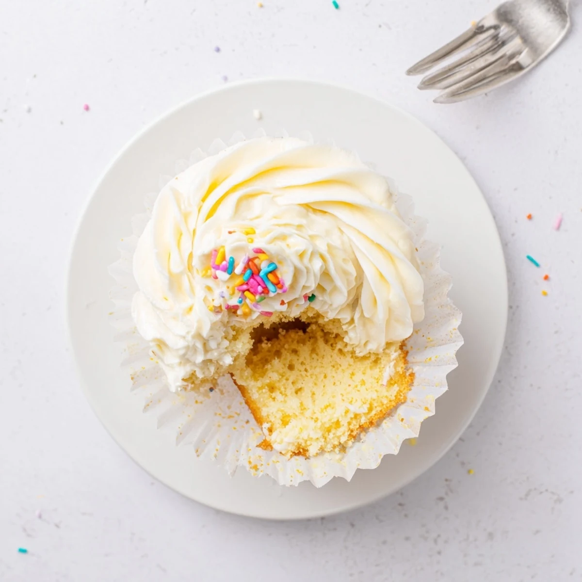 Freshly baked vanilla cupcakes with smooth buttercream frosting and colorful sprinkles for celebrations