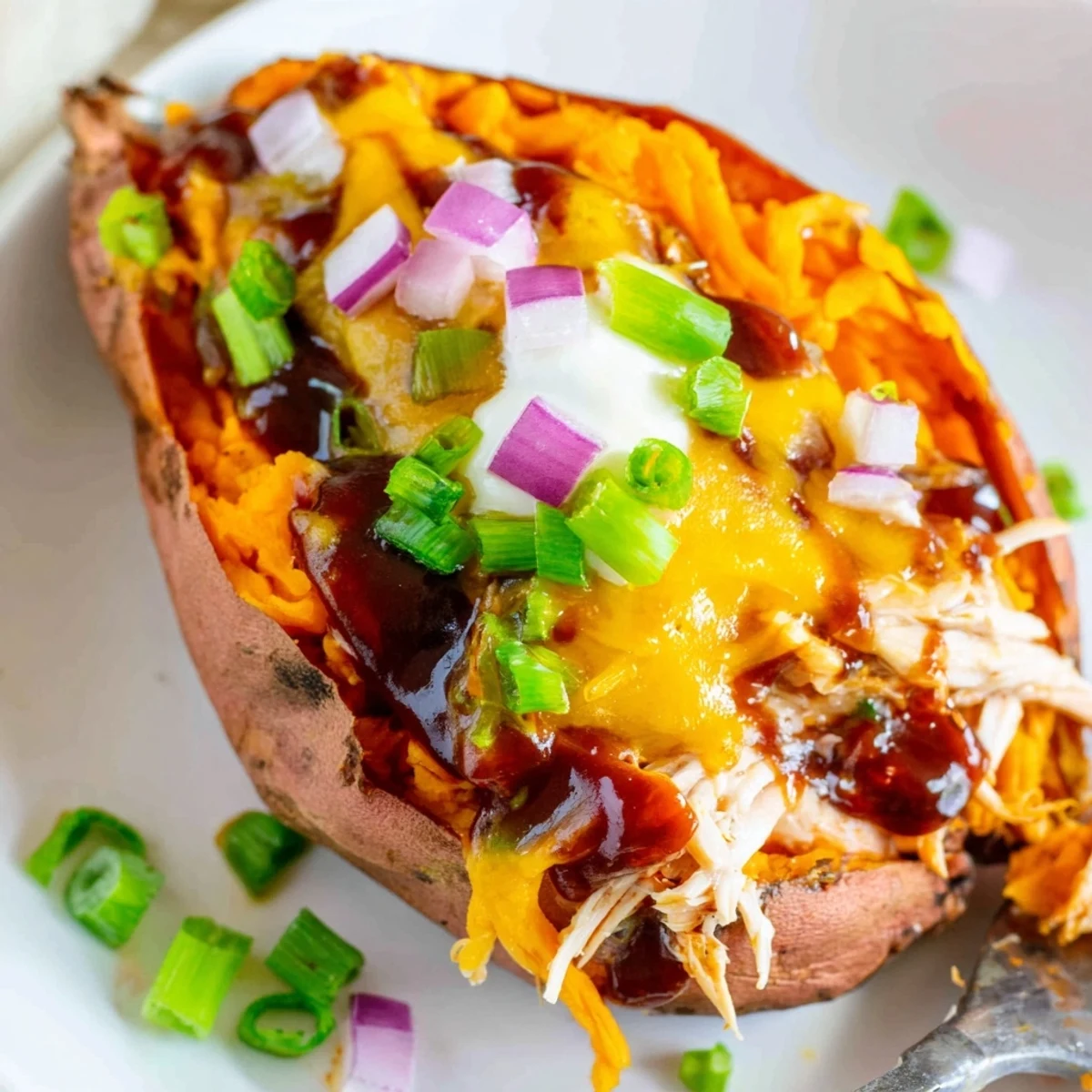 BBQ chicken stuffed sweet potatoes topped with green onions and a creamy sour cream dollop