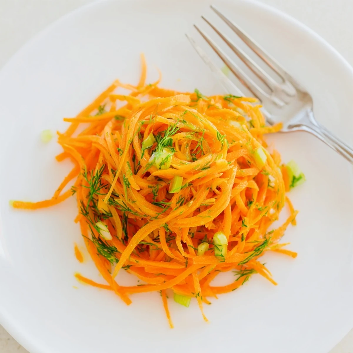 Tender julienned carrots in Marinated Lemon Dill Carrot Salad topped with scallions and dill