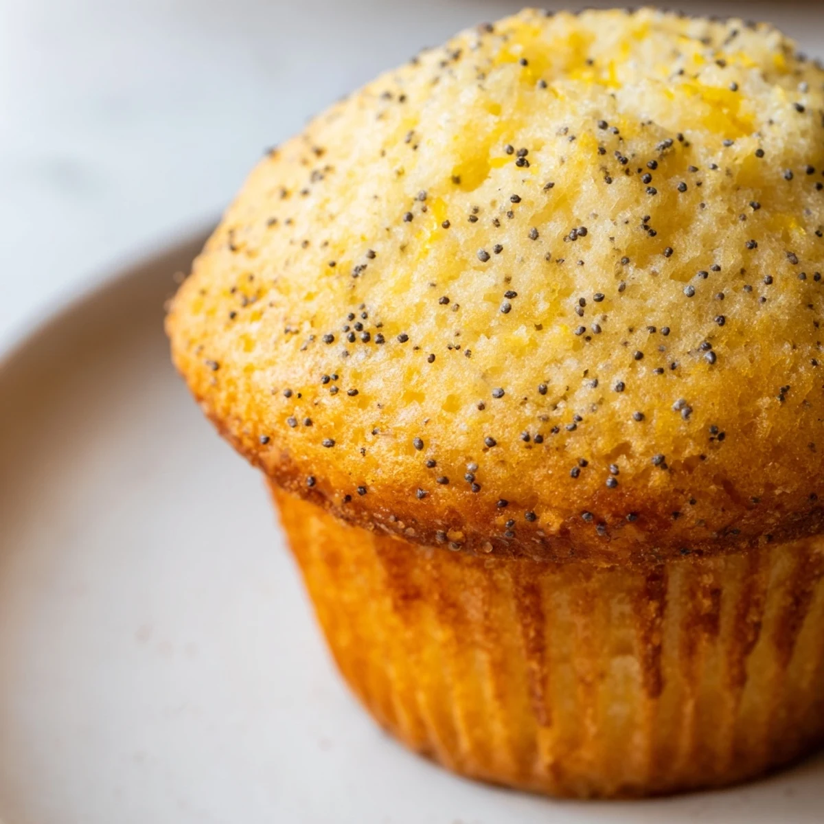 Golden lemon poppy seed muffins with domed tops fresh from the oven