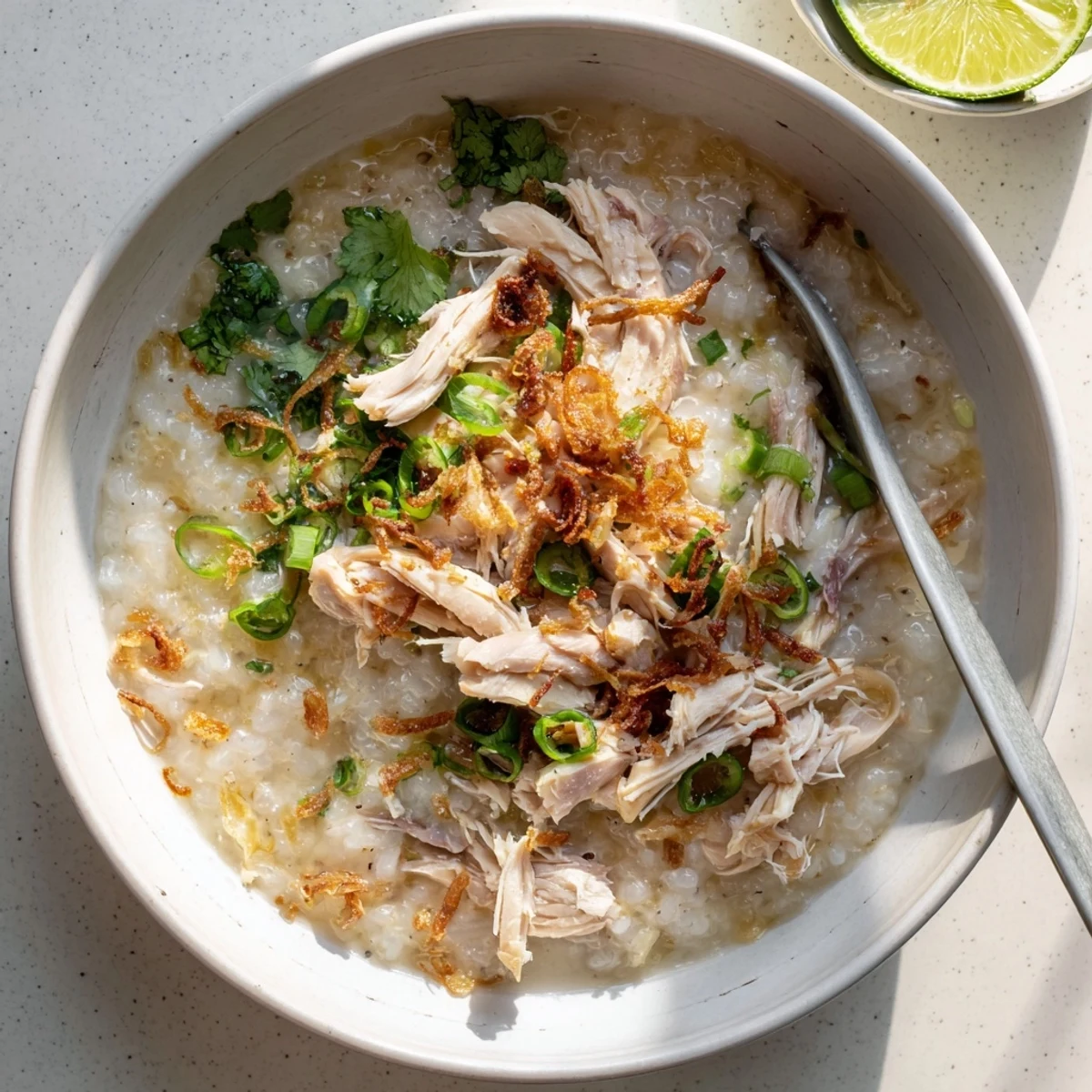 Creamy cháo gà garnished with fried shallots, vibrant herbs, and juicy chicken pieces in a rich aromatic broth