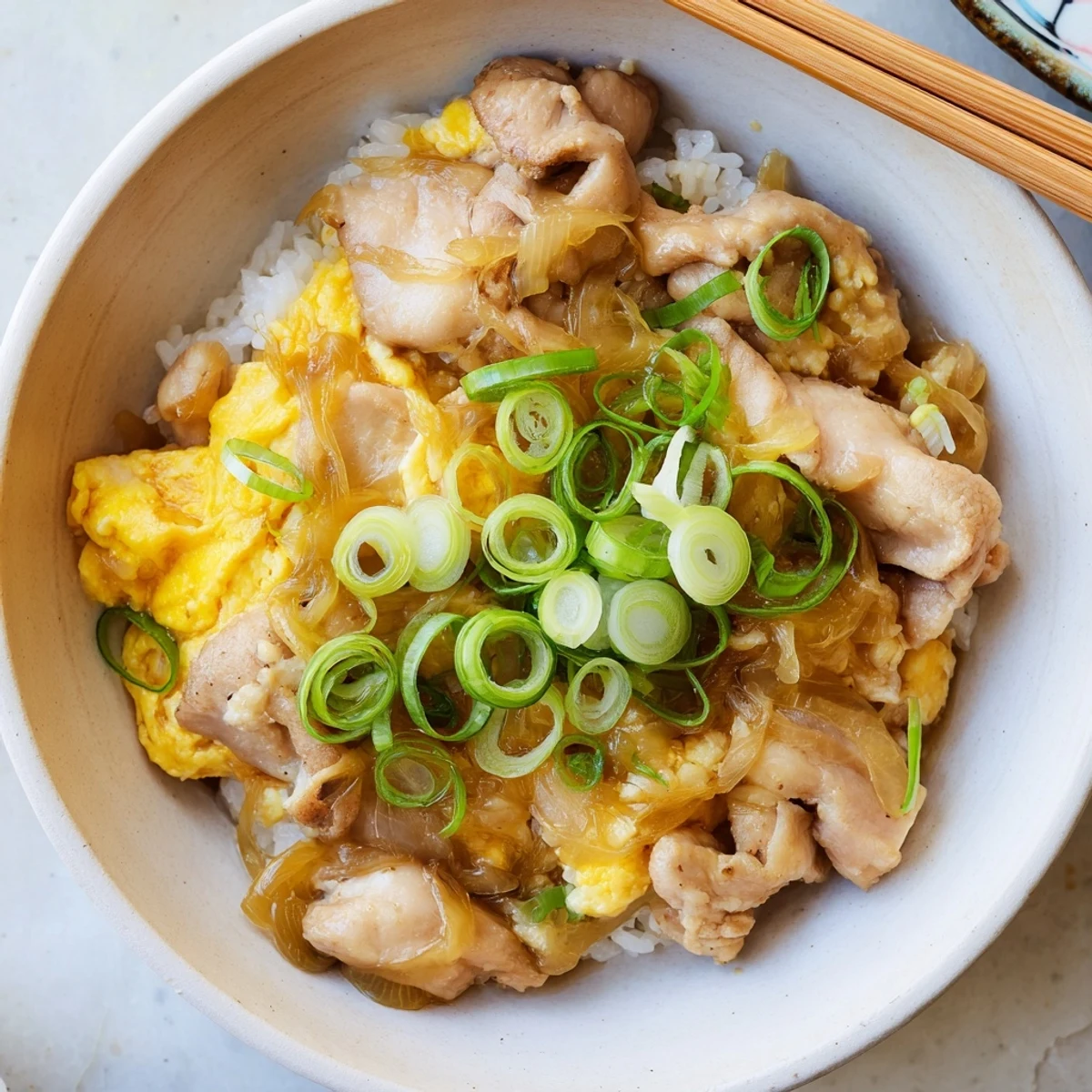 Steaming Japanese Oyakodon served in donabe with juicy chicken and silky egg over white rice