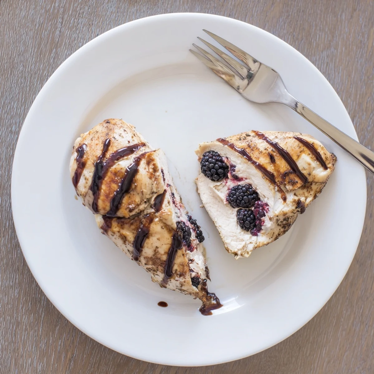 Succulent baked chicken breast sliced open to reveal creamy blackberry jalapeño stuffing with glossy honey balsamic glaze