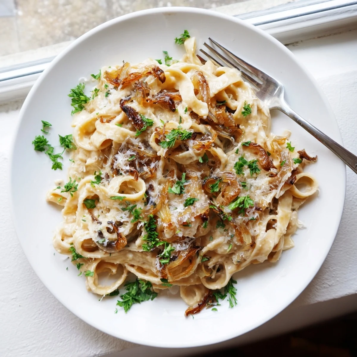 Golden caramelized onions coating fettuccine noodles in a rich velvety cream sauce with Parmesan