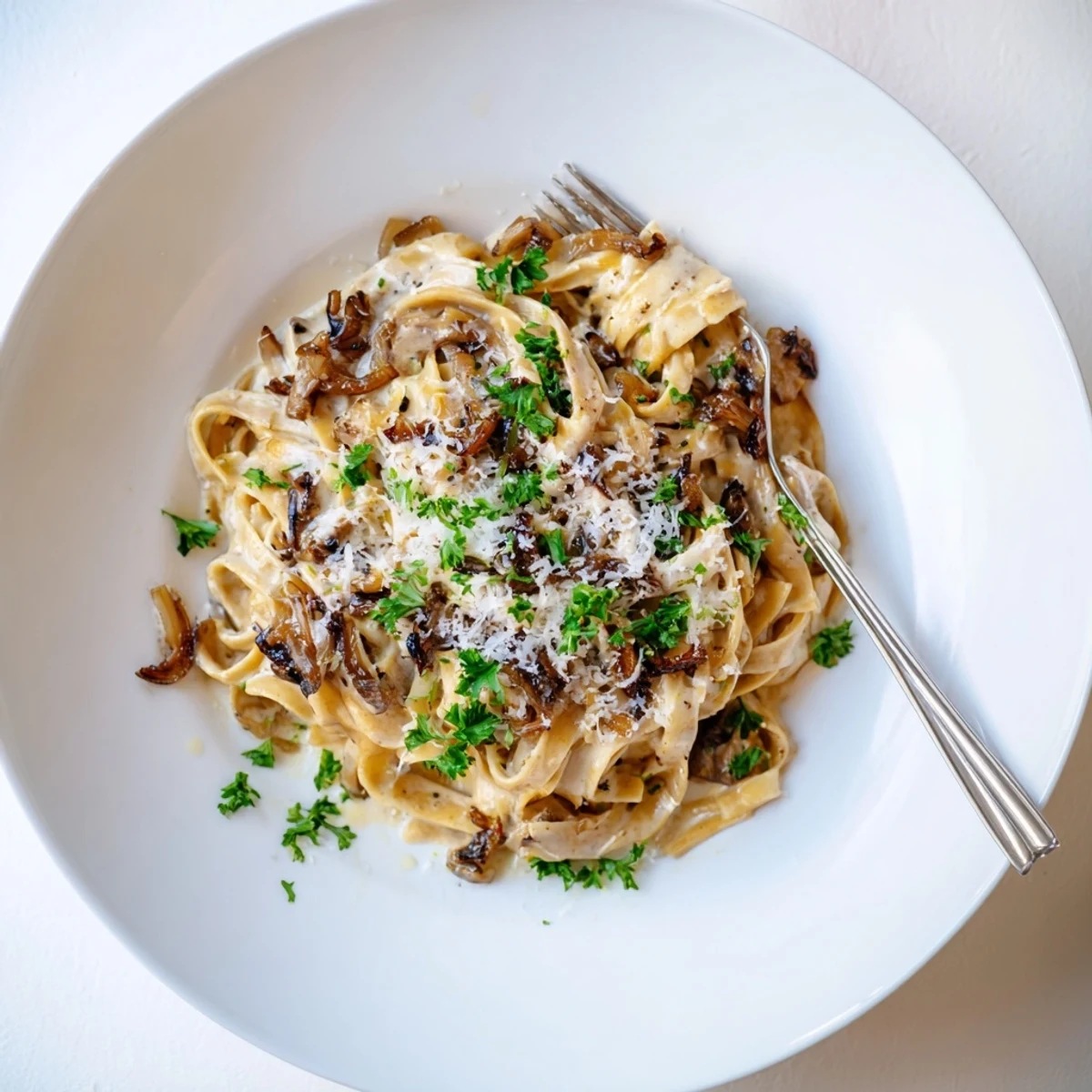 Creamy caramelized onion pasta dish served piping hot with golden brown onions and Parmesan sprinkles