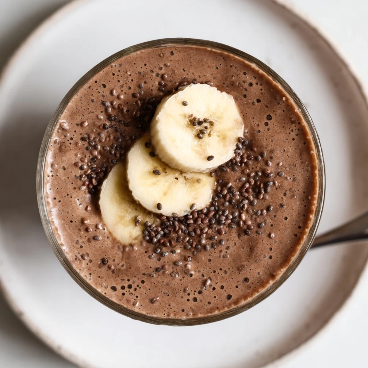 Creamy Raw Chocolate Banana Shake garnished with banana slices and cacao nibs