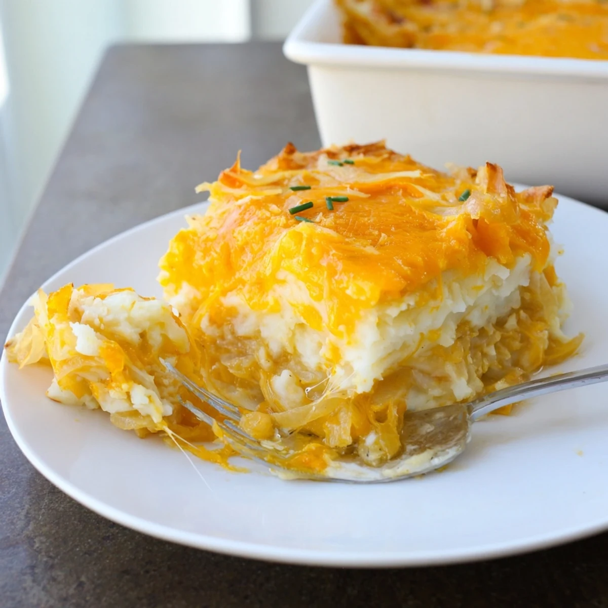 Creamy Cheesy Onion Mashed Potato Casserole layered with caramelized onions and served in a rustic baking dish