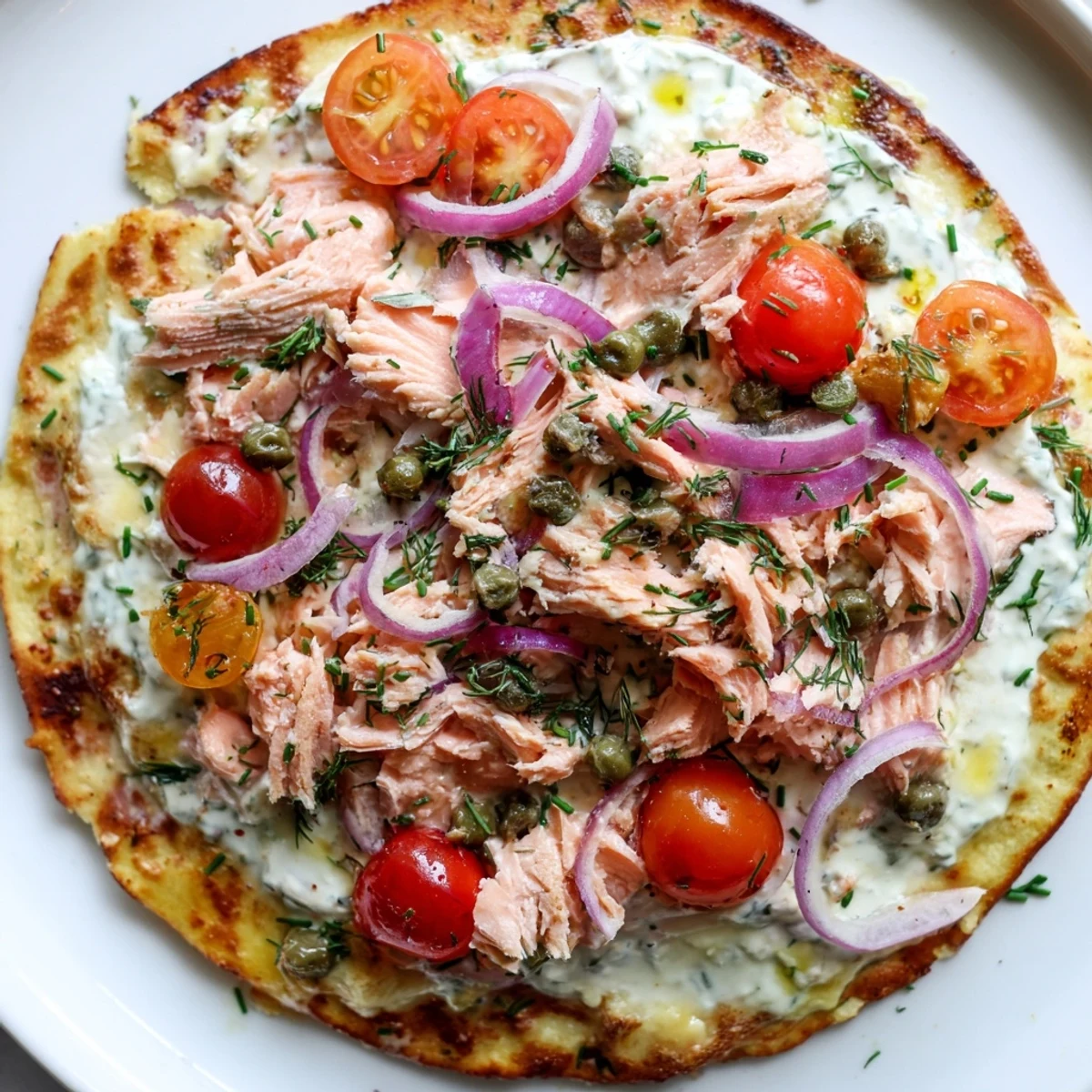 Crispy golden salmon tortilla pizza topped with melted mozzarella, red onion, and fresh dill