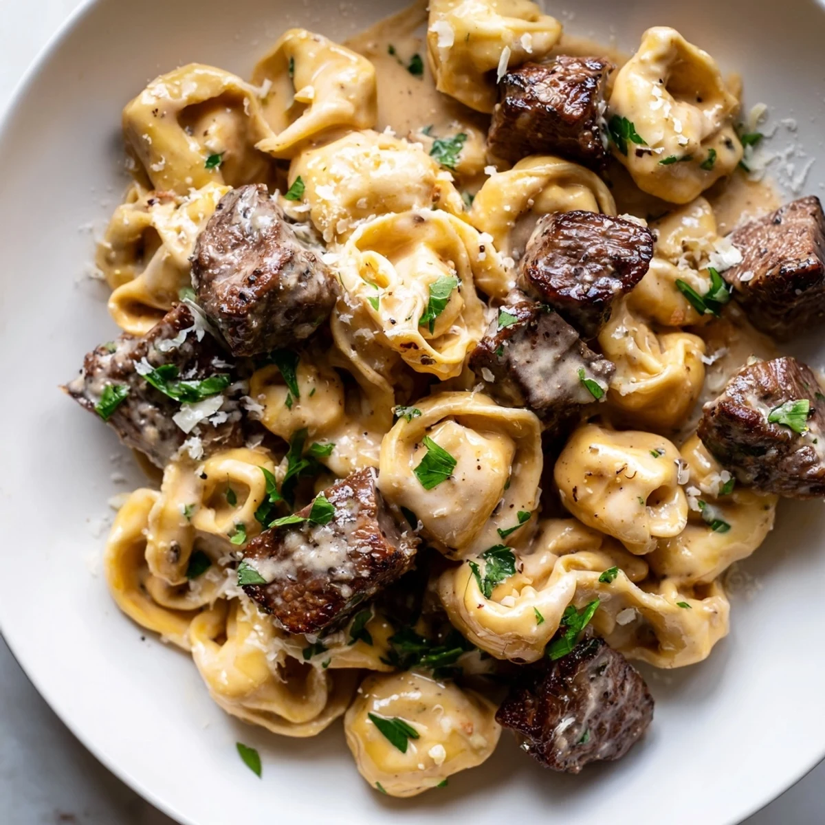 Creamy garlic steak tortellini served in a golden Parmesan sauce with fresh parsley