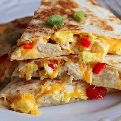 Pan-toasted Chicken Breakfast Quesadilla sliced into wedges, served with salsa and avocado