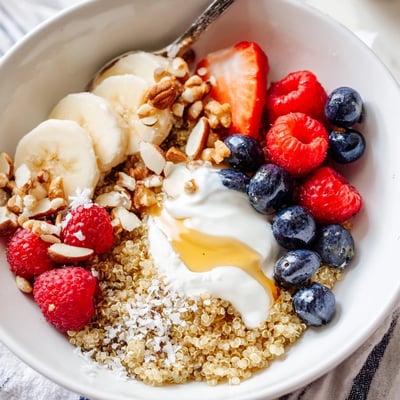 Warm Quinoa Breakfast Bowl topped with sliced banana, honey drizzle, toasted coconut